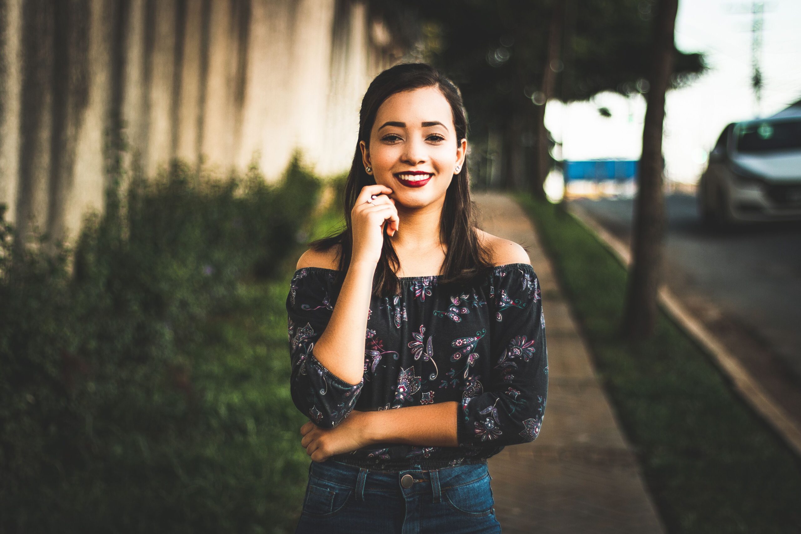 Smiling woman in casual wear posing confidently on a sunny city street.